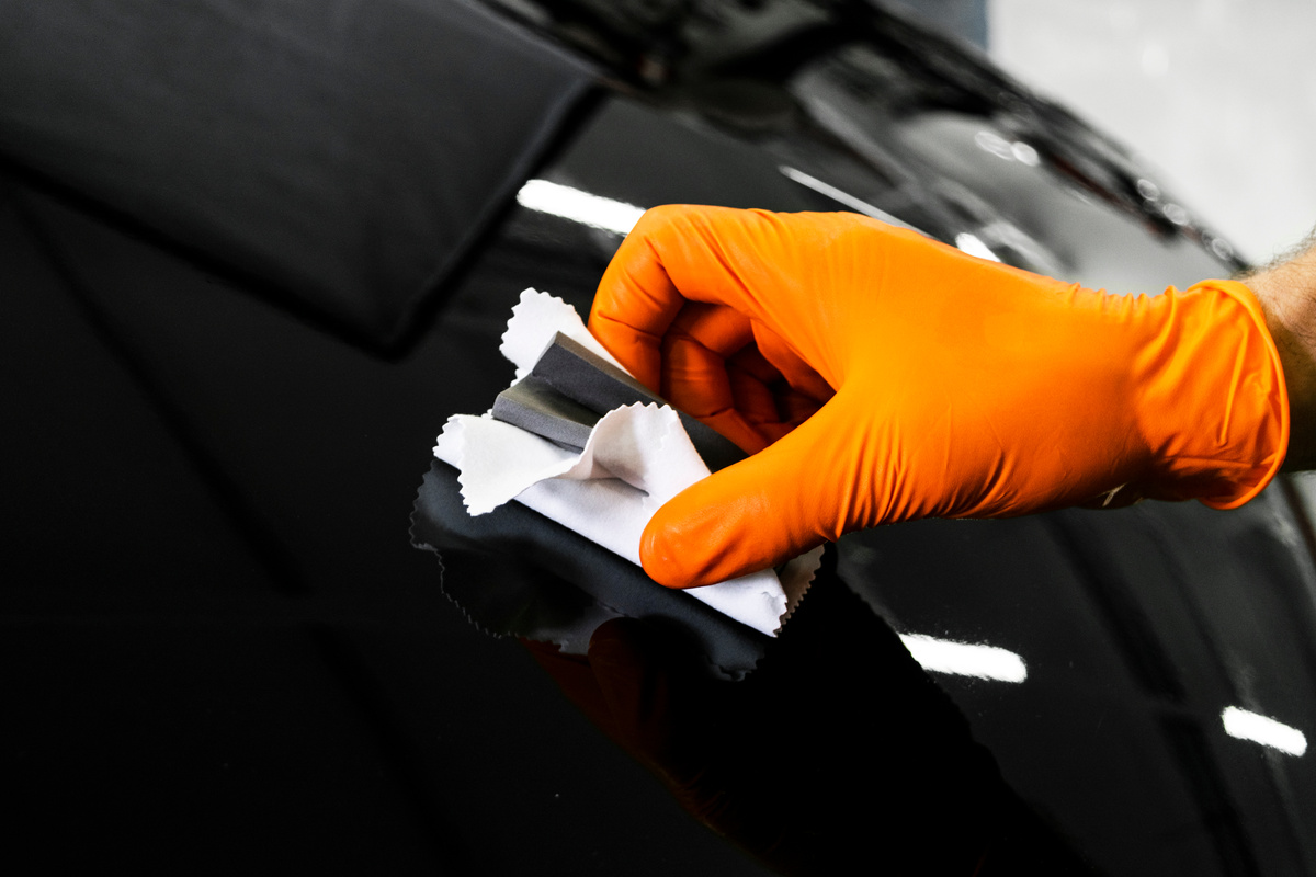 Car polish wax worker hands polishing car. Buffing and polishing vehicle with ceramic. Car detailing. Man holds a polisher in the hand and polishes the car. Tools for polishing